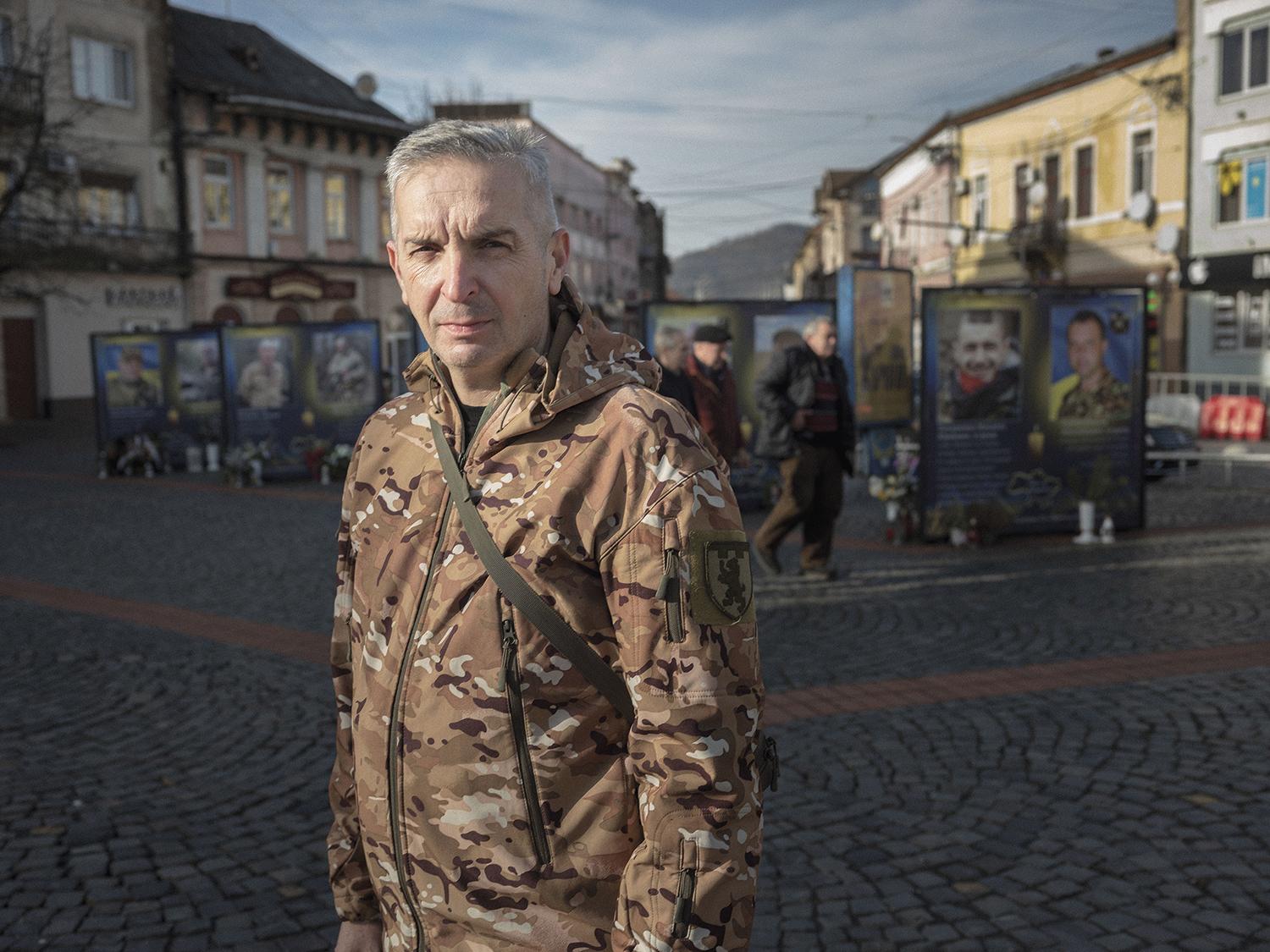 Seržant Bohdan počas krátkej dovolenky na hlavnom námestí Mukačeva pred fotografiami jeho padlých spolubojovníkov zo Zakarpatského bataliónu.