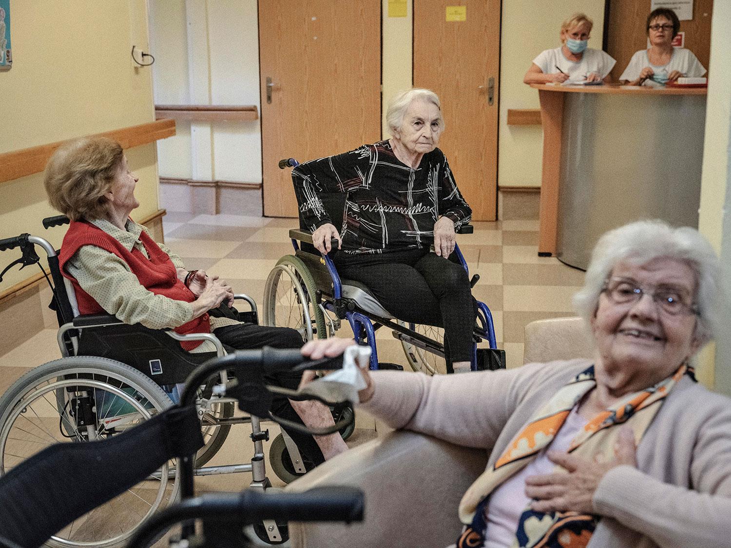 V popredí obyvateľky Archy 89-ročná Mária Hlôšková s 87-ročnou kamarátkou Evou Skočekovou čakajú na obed vo vstupnej chodbe zariadenia pre seniorov.