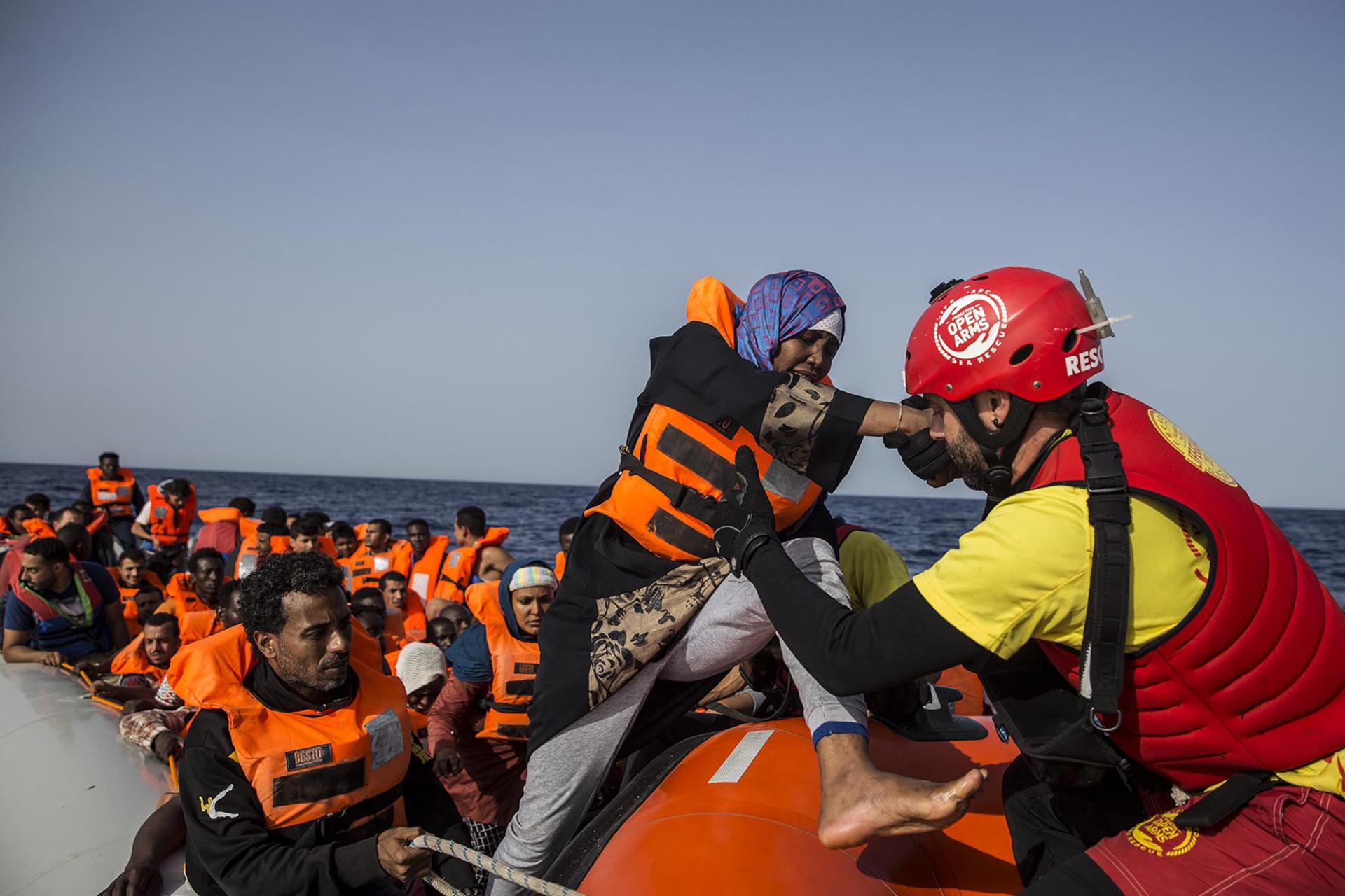30. júna 2018, Stredozemné more: Záchranári zo španielskej mimovládnej organizácie Proactiva Open Arms pomáhajú Afričanke dostať sa z člna. 