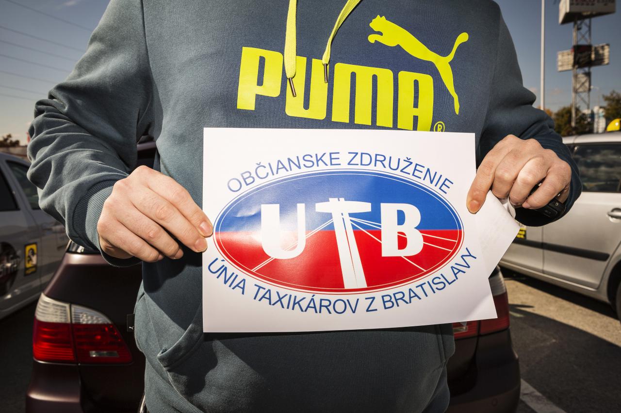Taxikár s vytlačeným logom Únie taxikárov z Bratislavy, ktoré si autá v kolóne lepili okno.