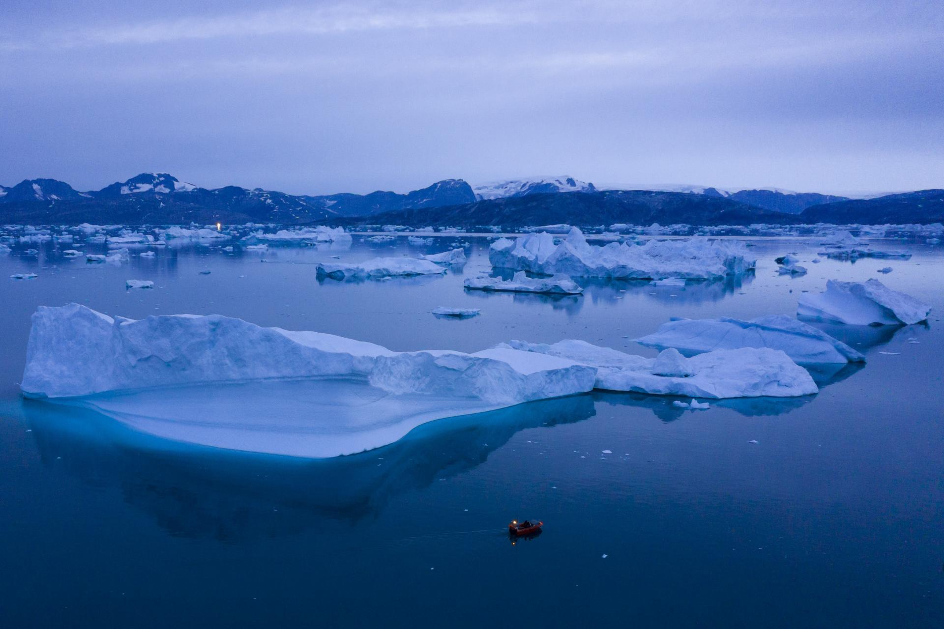 15. august 2019 Grónsko, Dánske kráľovstvo: Loď sa uprostred noci plaví popri veľkých ľadovcoch v blízkosti mesta Kulusuk vo východnej časti Grónska.