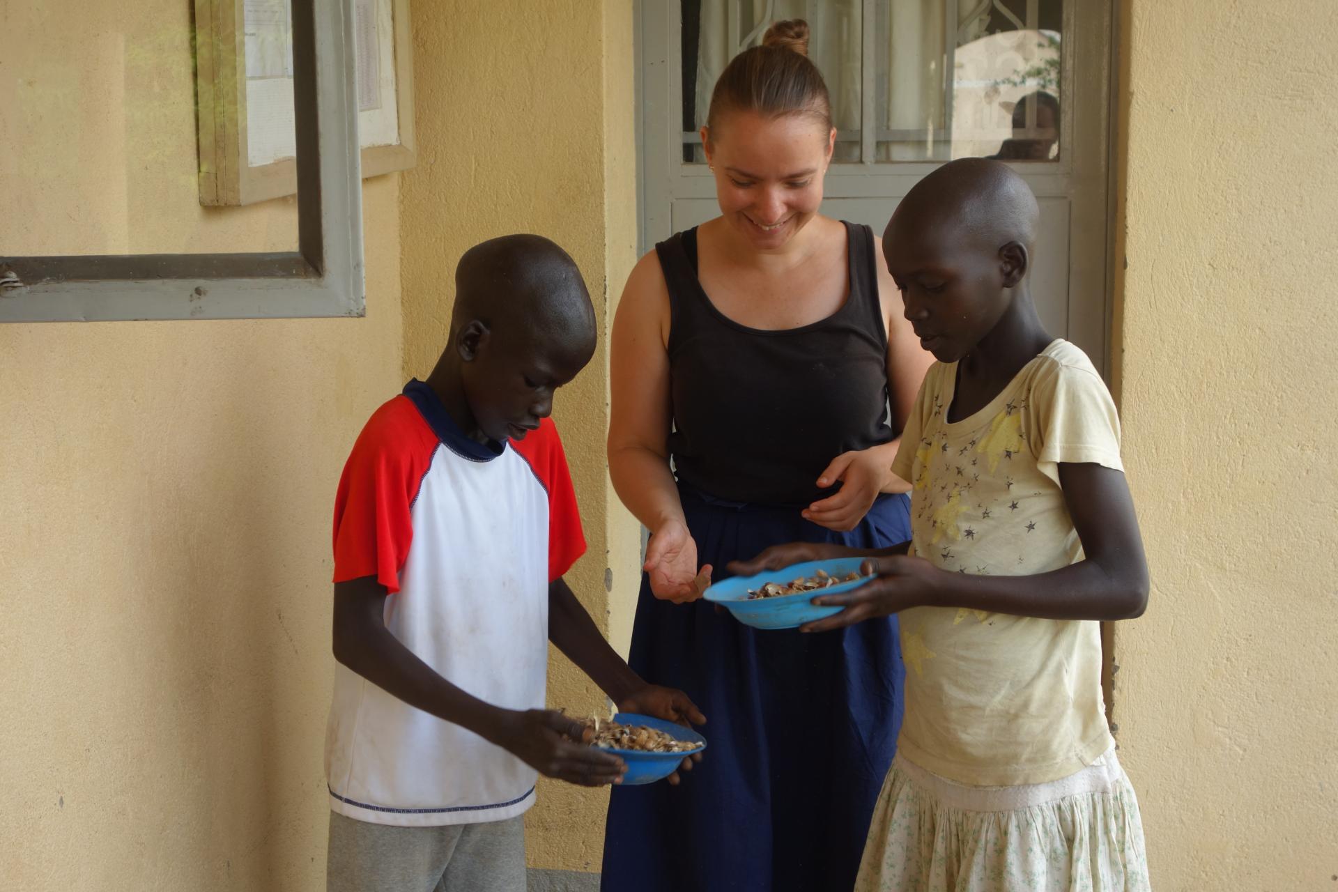 Vo voľných chvíľach deti lúpali arašidy. Dobrovoľníčke Veronike ukazujú, ako vytriediť šupky od orieškov.