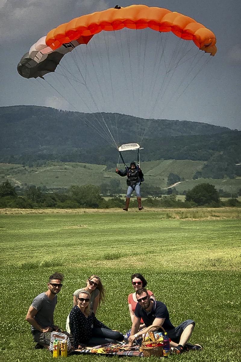 Štáb piknikuje a v pozadí pristáva kaskadér – Štefánik.