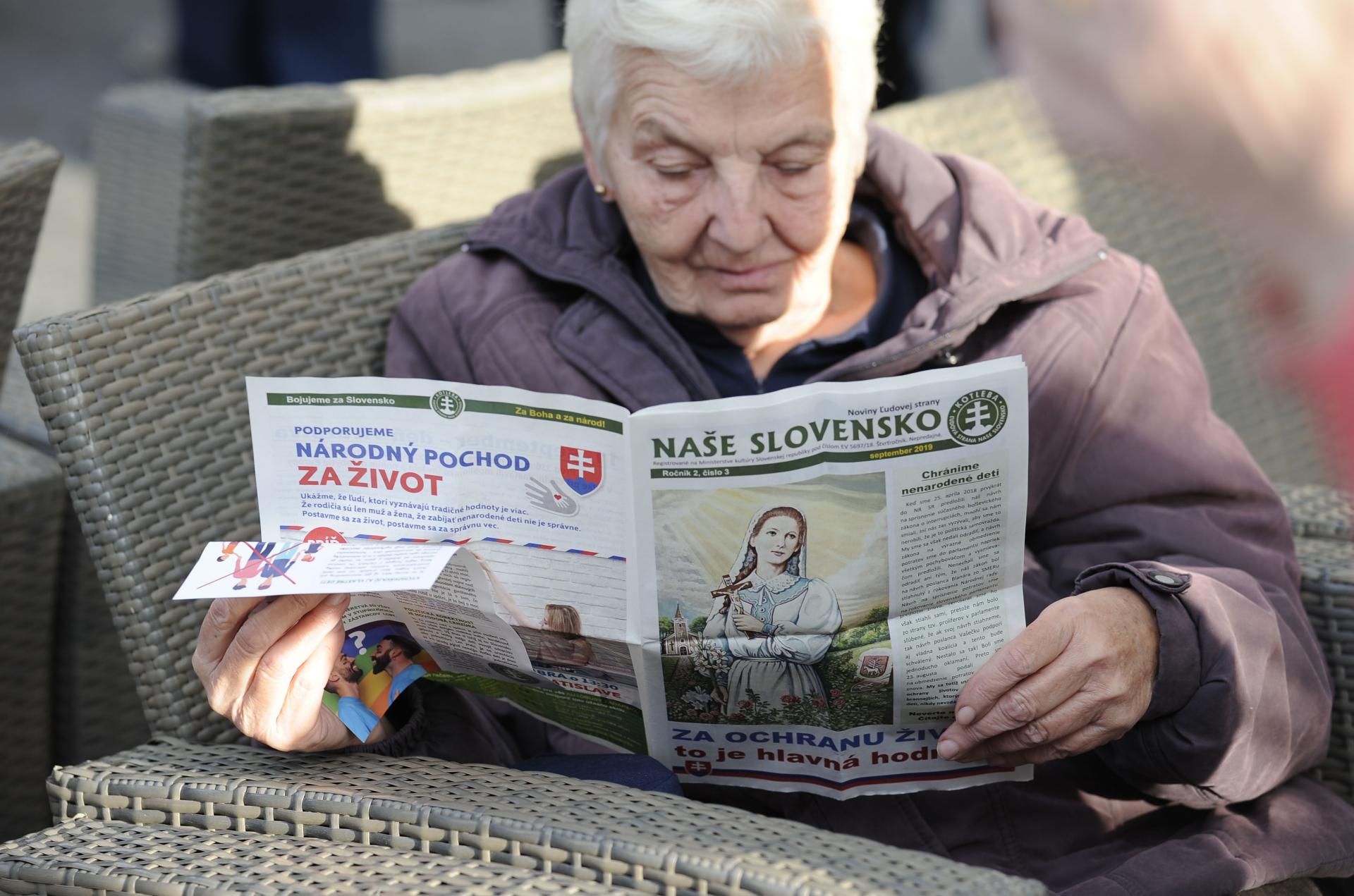 17. október 2019 Trenčín: Počas zhromaždenia strany Kotlebovci - Ľudová strana Naše Slovensko na Mierovom námestí v Trenčíne si pani číta o víziách a sľuboch kotlebovcov.