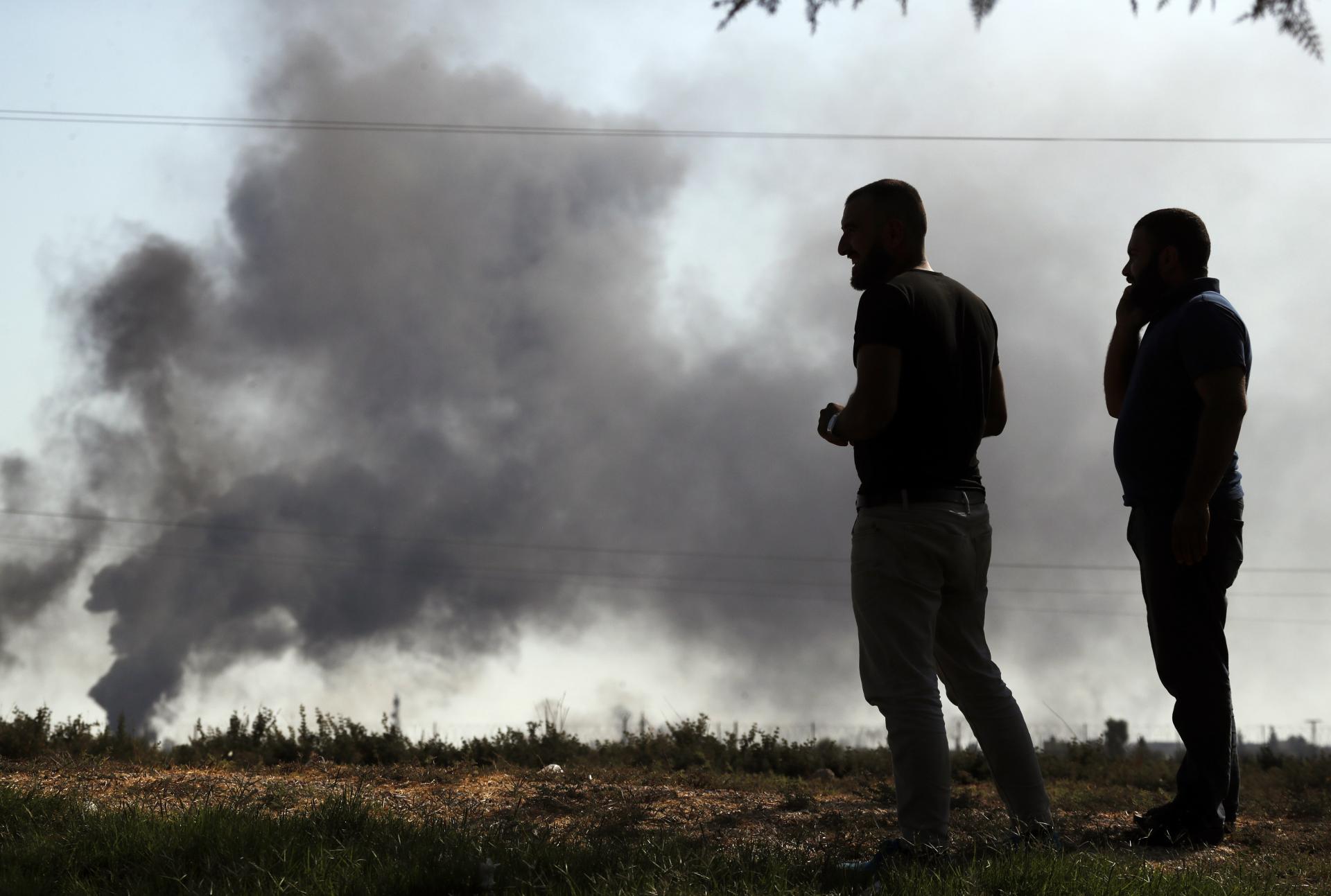 10. október 2019 Akcakale, Turecko: Muži na hraniciach sledujú dym, ktorý stúpa z cieľov zasiahnutých na severovýchode Sýrie.