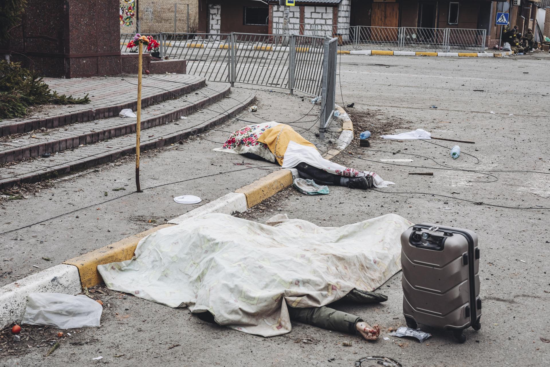 Zakryté mŕtve telá na uliciach mesta Irpiň. 