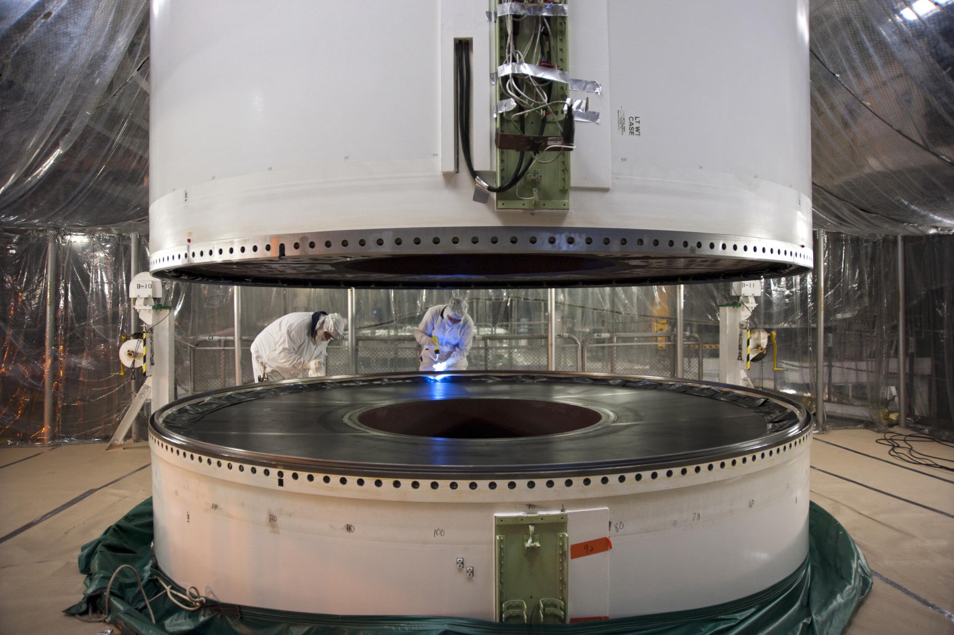 Spájanie dvoch segmentov pomocnej rakety na pevné palivo. Tmavá hmota vo vnútri je samotné palivo, ktoré horí po celej dĺžke rakety, od stredu ku stenám.