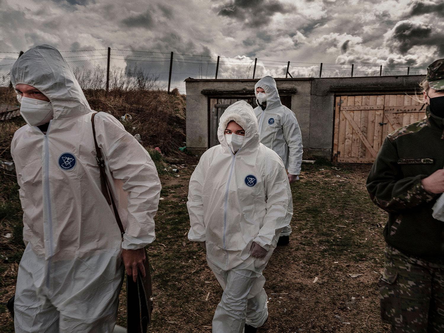 14. apríl 2020 Spišské Vlachy, Slovensko: Všetky uverejnené fotografie sú z uzavretej miestnej časti Dobrá Voľa, ktorá sa nachádza v karanténe obklopená policajtmi a vojakmi. Dnu môže ísť len človek oblečený v bielom skafandri. Ak sa návlek poškodí, osoba automaticky ostáva dnu v karanténe, tvrdí policajt, ktorý hliadkuje pri zatarasenom vchode do osady. Potraviny, ale aj stavebný materiál na opravu domov, si môžu obyvatelia vyzdvihnúť len pri páske.