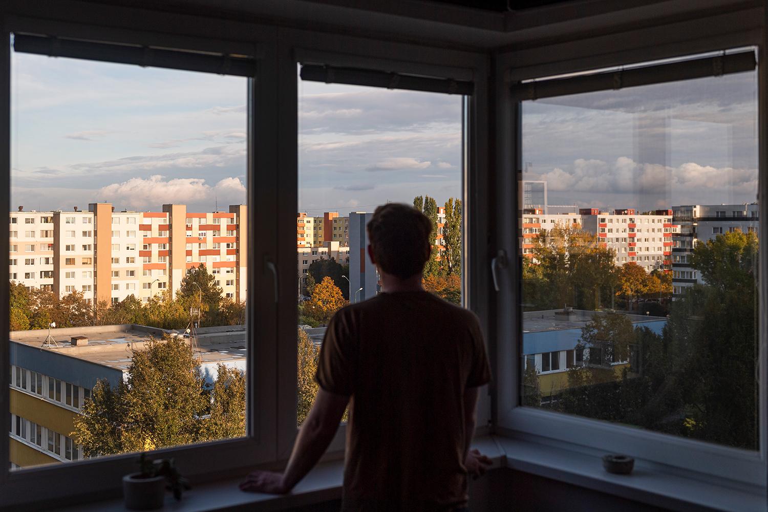 24. október 2020 Bratislava: Muž sa pozerá z okna svojho bytu v bratislavskej mestskej časti Podunajské Biskupice. Od 24. októbra do 1. novembra 2020 platí na celom Slovensku zákaz vychádzania s výnimkami, ako sú cesta do práce alebo na nákup, prípadne vychádzky do prírody. 