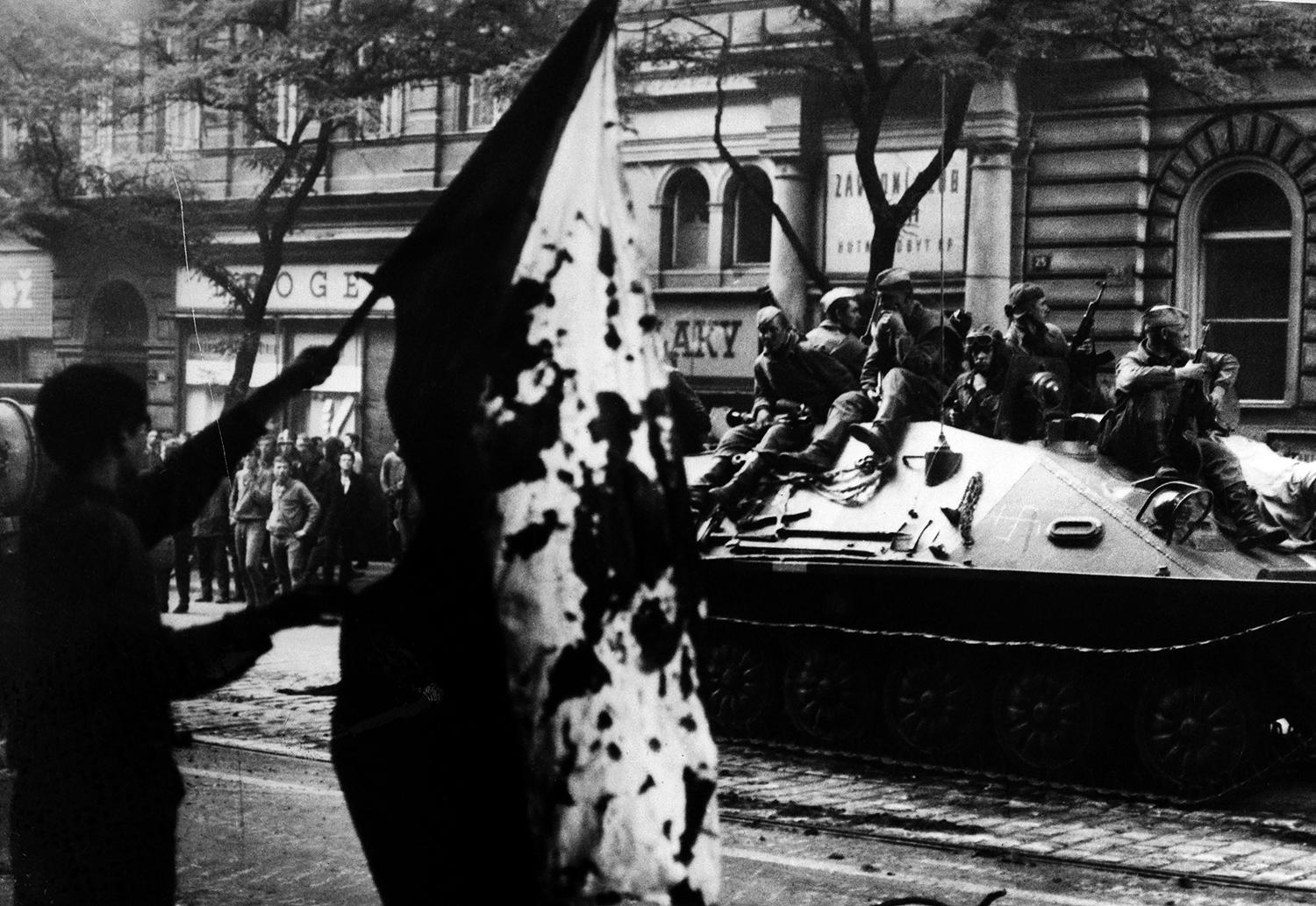 24. august 1968 Praha, Československo: Ľudia v uliciach mesta mávajú krvavou vlajkou pred zrakmi sovietskych vojakov, ktorých poslala Moskva, aby potlačila rodiace sa demokratické procesy v krajine.