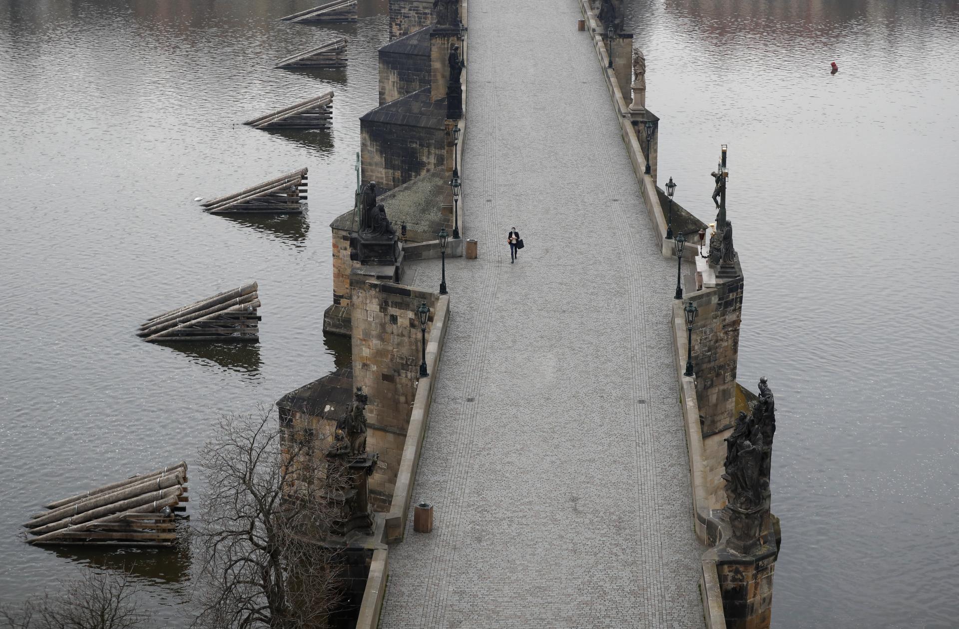20. marec 2020 Praha, Česká republika: Žena prechádza cez takmer úplne prázdny Karlov most v Prahe, dominantnej historickej a turistickej pamiatke v Česku.