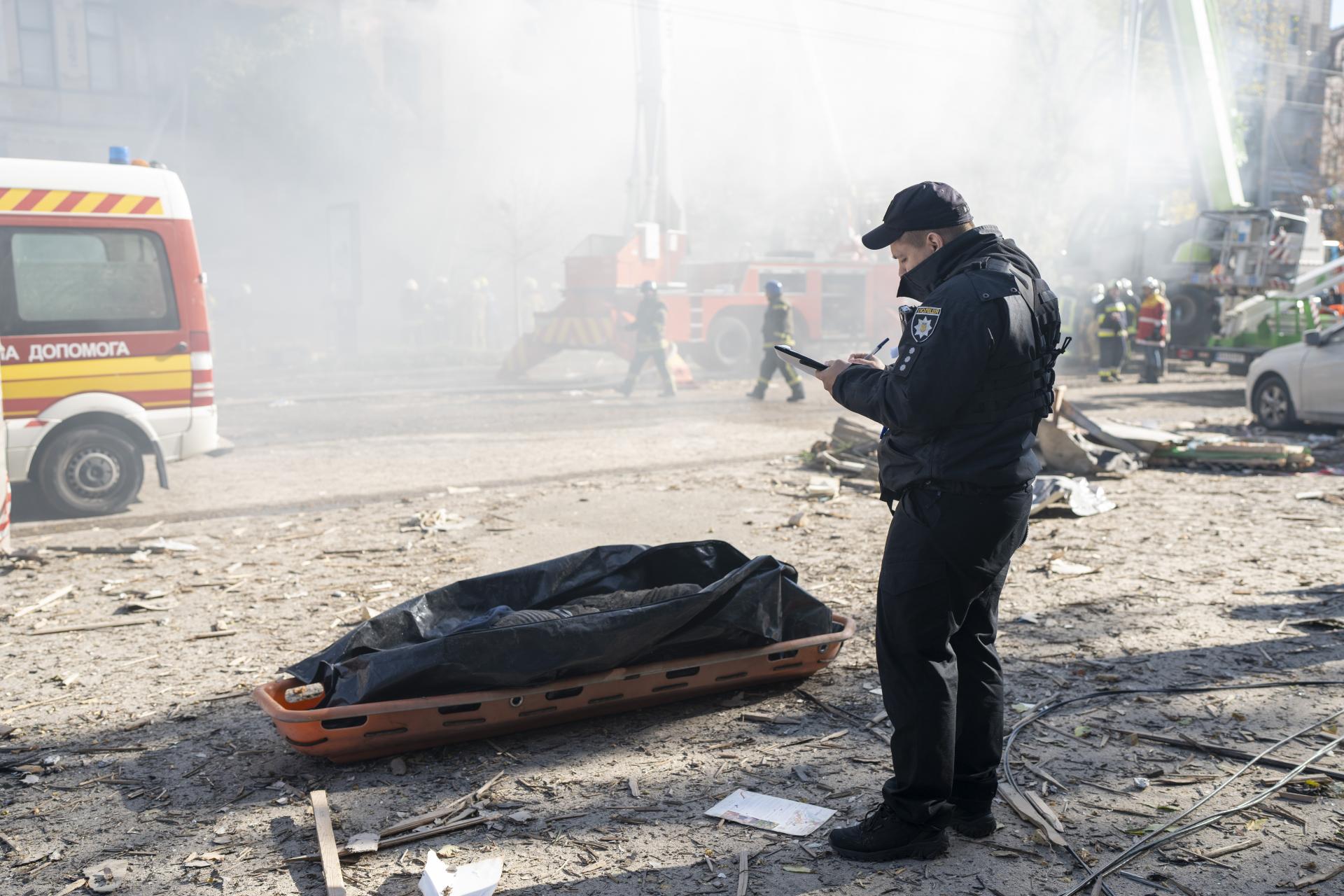 Policajst stojaci vedľa obete dronových útokov v Kyjeve, 17.10.2022