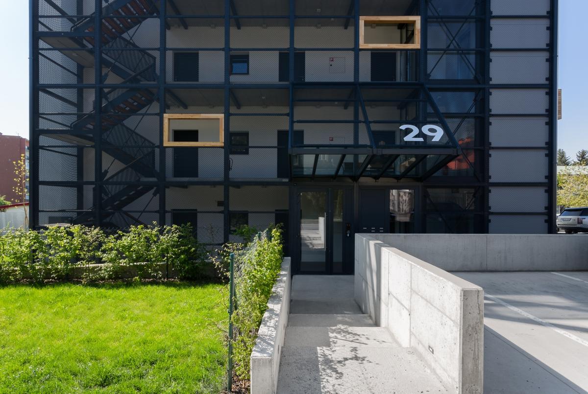 Záber na vchod atypického, no na prvý pohľad obyčajného bytového domu.