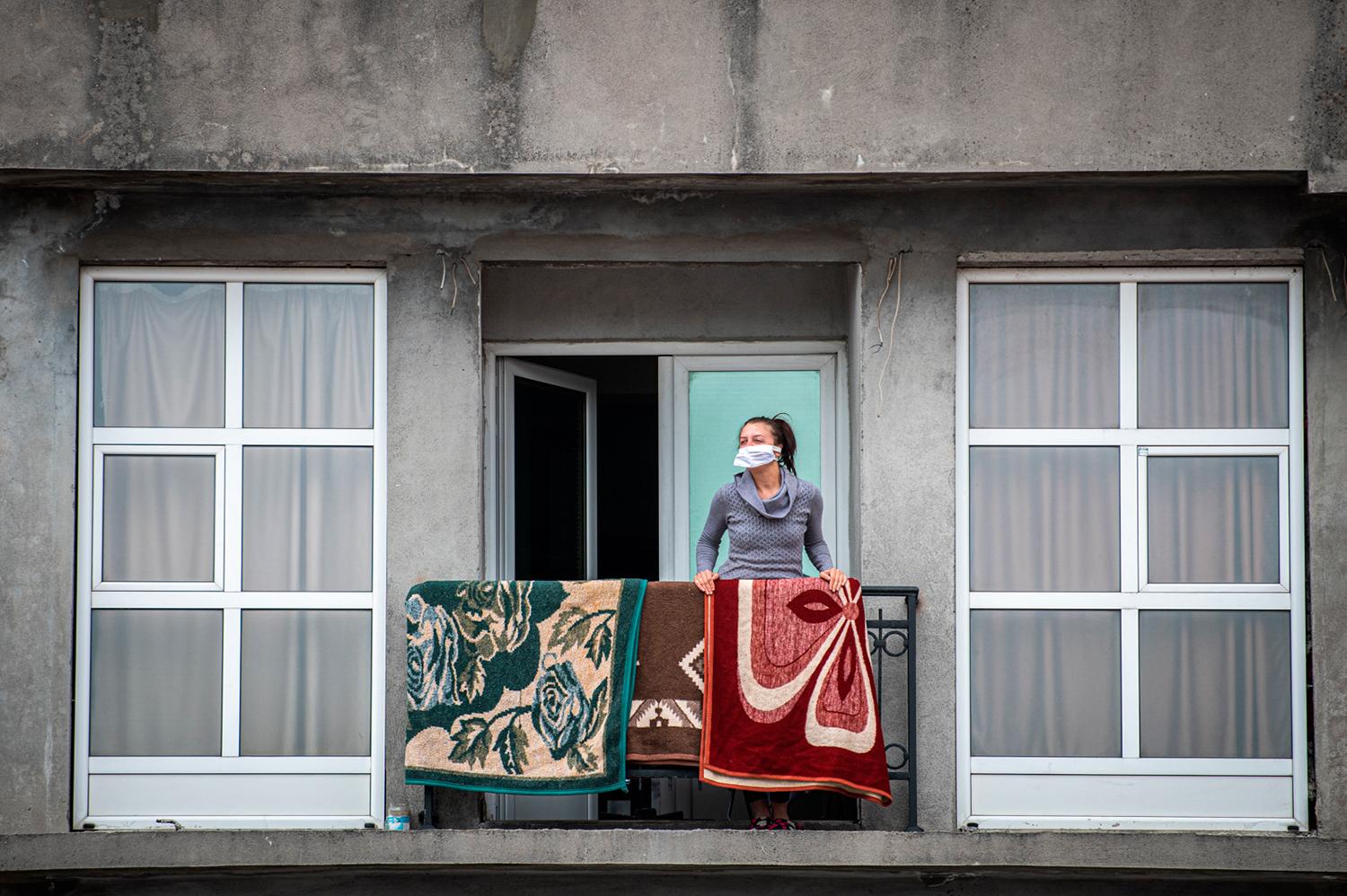 29. marec 2020 Tuzi, Čierna Hora: Žena v rúšku na balkóne svojho bytu počas lockdownu vyhlásenému pre pandémiu Covid-19.