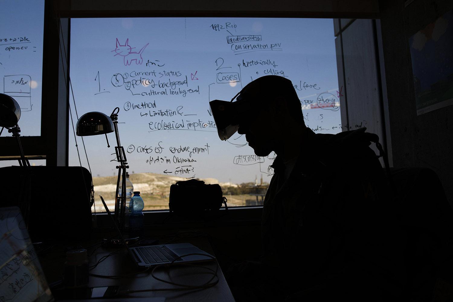 21. február 2017 Beer Ševa, Izrael: Príslušník izraelských ozbrojených síl s okuliarmi na virtuálnu realitu počas hackathonu v priestoroch firmy We Work Studios. Izraelská obrana pred kyberútokmi stojí na vzdelaných ľuďoch a startupovom prostredí.